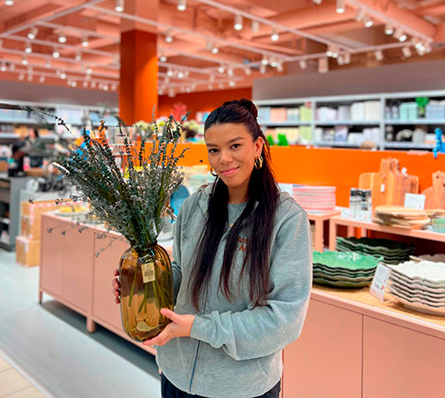 Medarbejder fra Basic & More der holder vase frem med kunstige blomster i