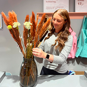 Medarbejder fra Basic & More i Slagelse, står med vase med blomster i og tilpasser buketten.
