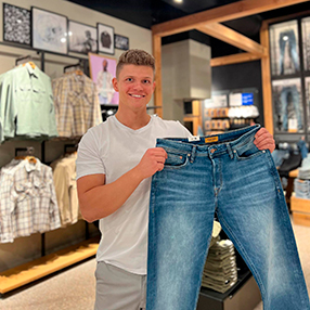 Medarbejder fra Jack & Jones i Slagelse, står med et par lyseblå jeans. 