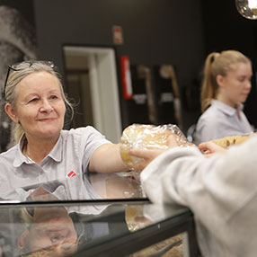Ekspedient fra Kvickly bager i Slagelse rækker frisksmurt morgenbrød til kunde