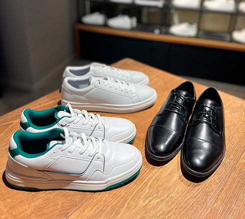 Hvide sneaks, sorte businesssko og hvide sneaks med grønne detaljer på bord fra Jack&Jones i Slagelse.