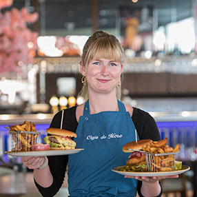 Medarbejder holder to burgere på tallerken, der er klar til at blive serveret.