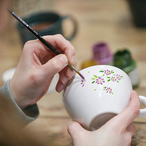 Medarbejder der maler blomster på en gammel kop
