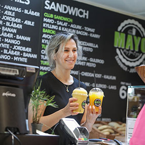 Ekspedient står med to friskpressede juice hos sandwich og juicebaren Mayo i Slagelse
